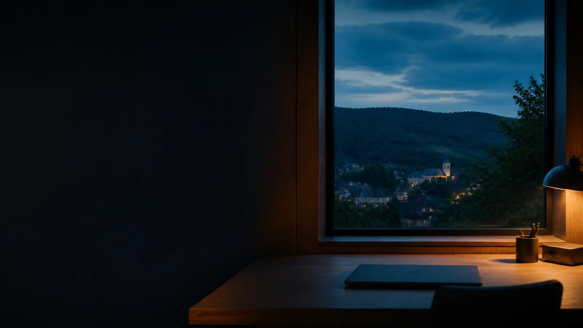 Schreibtisch am Fenster mit Blick auf ein Dorf in den Hügeln bei Nacht